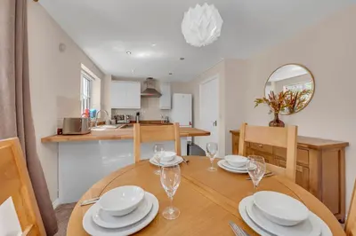 a dining room and kitchen with a wooden table and chairs at The Grange Luxe3, 4 Bedroom House,5-beds,Spacious,contractor,family,Internet,free parking,group,study,relocation,easily accessible in Ipswich,Kesgrave in Ipswich
