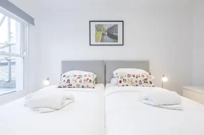 a white bedroom with two beds with pillows at Refurbished High Spec CENTRAL Family Home in Cambridge