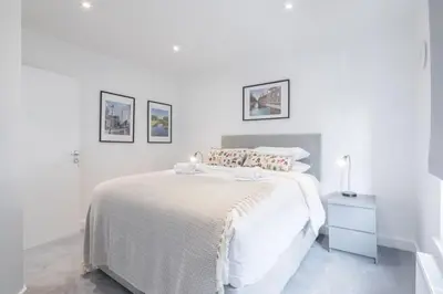a white bedroom with a bed and a night stand at Refurbished High Spec CENTRAL Family Home in Cambridge