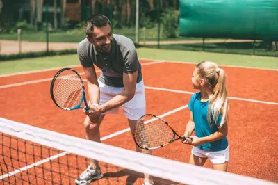 a man and a girl holding tennis rackets on a tennis court at Stunning Lodge For Hire At Carlton Meres In Suffolk Ref 60013M in Saxmundham