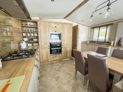 a kitchen with a table and a stove top oven at Modern Caravan With Large Decking Area, Ref 60057Ch in Saxmundham