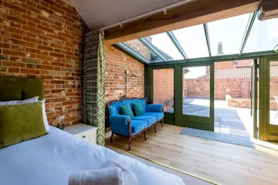 a bedroom with a bed and chairs in a brick wall at Alde Bay Farm - Barn Owl Sanctuary in Aldeburgh