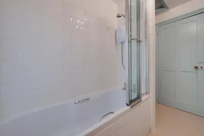 a white bathroom with a shower and a glass door at 3 Bed in Aldeburgh oc-marg in Aldeburgh