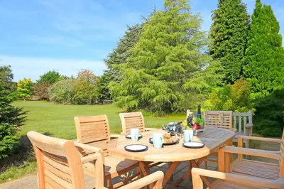 a wooden table with chairs in a garden at 3 Bed in Aldeburgh oc-10nw in Aldeburgh