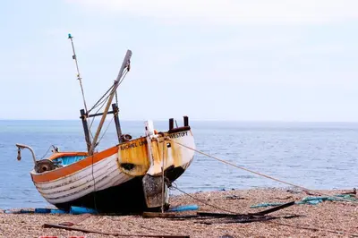 a boat sitting on the beach next to the water at 2 Bed in Aldeburgh oc-prd in Aldeburgh