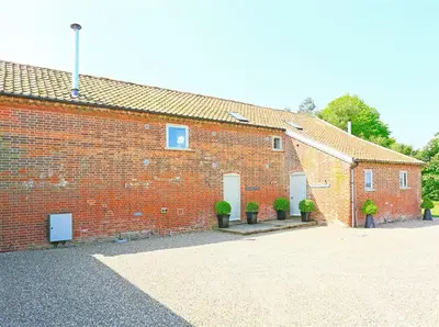 a brick building with potted plants in front of it at 6 Bed in Knodishall oc-bil in Aldringham