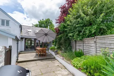 a patio with a wooden table and an umbrella at 4 Bed in Eastbridge oc-bricot in Theberton