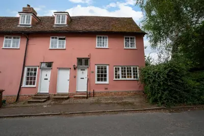 a pink house with white doors on a street at 2 Bed in Lavenham oc-24ss in Lavenham