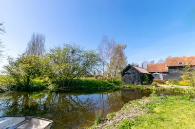 a river with a barn and a boat on it at 2 Bed in Rumburgh oc-dgf in Rumburgh