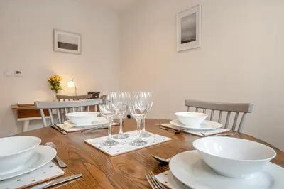 a wooden table with wine glasses and plates on it at 7 Bed in Aldeburgh oc-midba in Aldeburgh