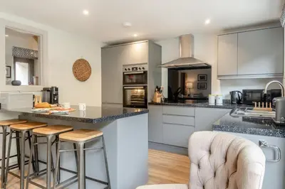 a kitchen with white cabinets and a island with bar stools at 7 Bed in Aldeburgh oc-midba in Aldeburgh