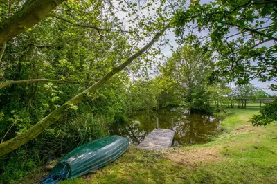 a canoe sitting on the grass next to a pond at 5 Bed in Finningham oc-obhf in Finningham