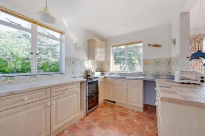a large kitchen with white cabinets and windows at 3 Bed in Aldeburgh oc-spr in Aldeburgh