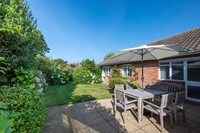 a patio with a table and chairs and an umbrella at 3 Bed in Aldeburgh oc-spr in Aldeburgh