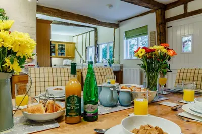 a dining room table with bottles of wine and flowers at 5 Bed in Metfield oc-stfarm in Metfield
