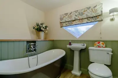 a bathroom with a tub and a toilet and a sink at 5 Bed in Metfield oc-stfarm in Metfield