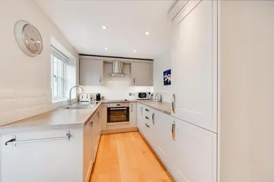 a kitchen with white cabinets and a clock on the wall at 2 Bed in Eye oc-slo in Wilby