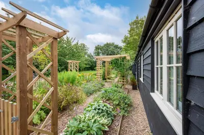 a garden with a wooden trellis next to a house at 3 Bed in Wilby oc-slowlo in Wilby