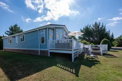 a blue tiny house with an umbrella and chairs at 2 Bed in Aldeburgh oc-har in Aldeburgh