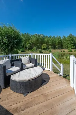 a wooden deck with two wicker chairs and a couch at 2 Bed in Aldeburgh oc-har in Aldeburgh