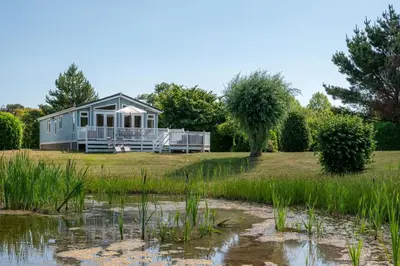 a tiny house on a lawn next to a pond at 2 Bed in Aldeburgh oc-har in Aldeburgh