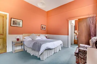 a bedroom with orange walls and a bed and a chair at 13 Bed in Tattingstone oc-tat26 in Tattingstone