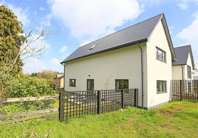 a white house with a black roof and a fence at 2 Bed in Leiston oc-cqa in Theberton