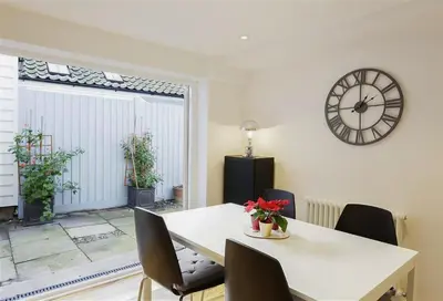 a dining room with a table and a clock on the wall at 2 Bed in Aldeburgh oc-tsc in Aldeburgh
