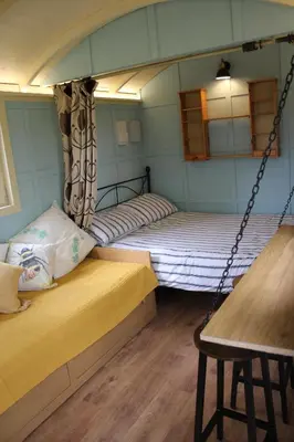 a couple of beds in a room with a swing at The Woodpecker shepherd hut in Elmswell