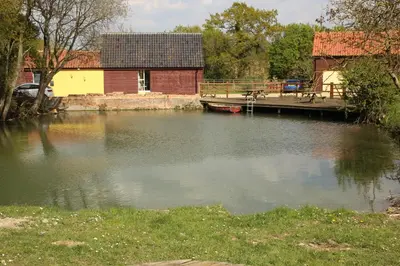 a body of water with a house and a dock at The Woodpecker shepherd hut in Elmswell