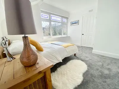 a bedroom with a bed and a table with a lamp at Charming Seaside Cottage in Leigh-on-Sea in Southend-on-Sea