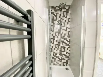 a glass shower in a bathroom with a tile wall at Charming Seaside Cottage in Leigh-on-Sea in Southend-on-Sea