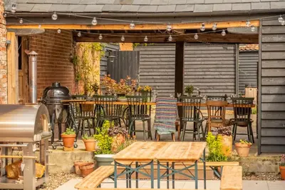an outdoor patio with tables and chairs and a grill at The Firs in Cratfield